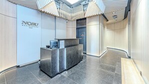 Un área de recepción moderna con un mostrador, un cartel de Nobu Residences West y un diseño de pared curva.