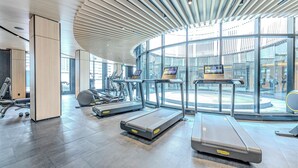 Un gimnasio moderno con cintas de correr, bicicletas estáticas y un amplio ventanal con vistas a la ciudad.