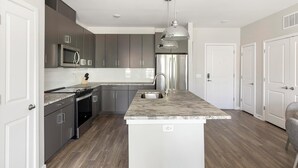 Una cocina moderna con gabinetes grises, electrodomésticos de acero inoxidable y encimera de mármol.