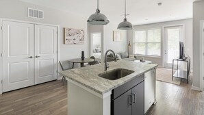 Una cocina moderna con una isla central, luces colgantes y un lavamanos empotrado.