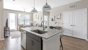 Een moderne keuken met een centraal eiland, een ingebouwde vaatwasser en hanglampen.