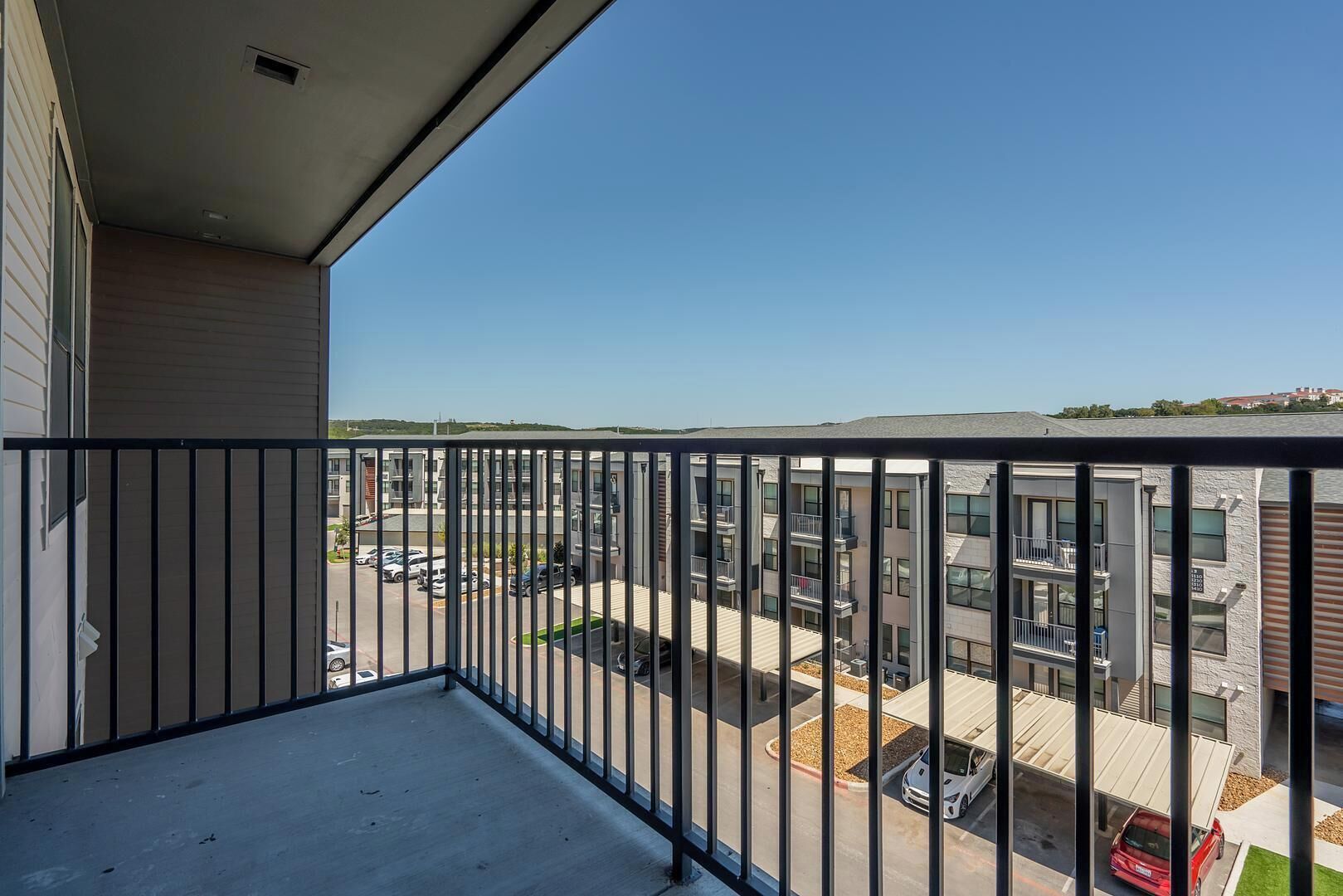 A balcony with a view of a parking lot and buildings.