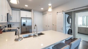 A modern kitchen with a central island, stainless steel appliances, and pendant lighting. - Landing | Amazing 1BD, Yoga Studio, Gym (San Antonio)