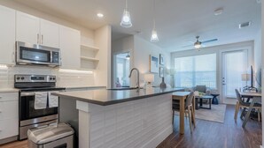 A modern kitchen with white cabinetry, stainless steel appliances, and a central island.
