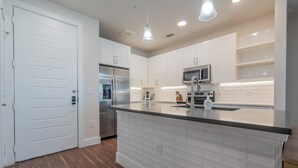 A modern kitchen with white cabinetry, stainless steel appliances, and a central island.