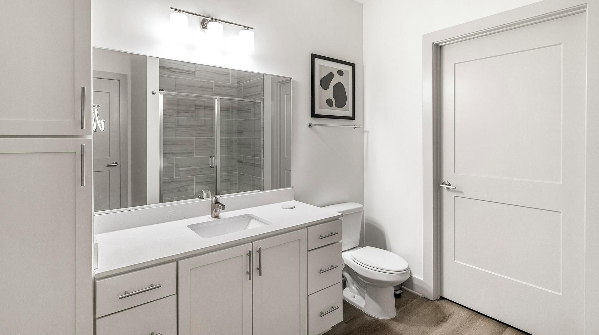 Ein modernes Badezimmer mit großem Spiegel, Waschbecken, Toilette und Duschkabine.
