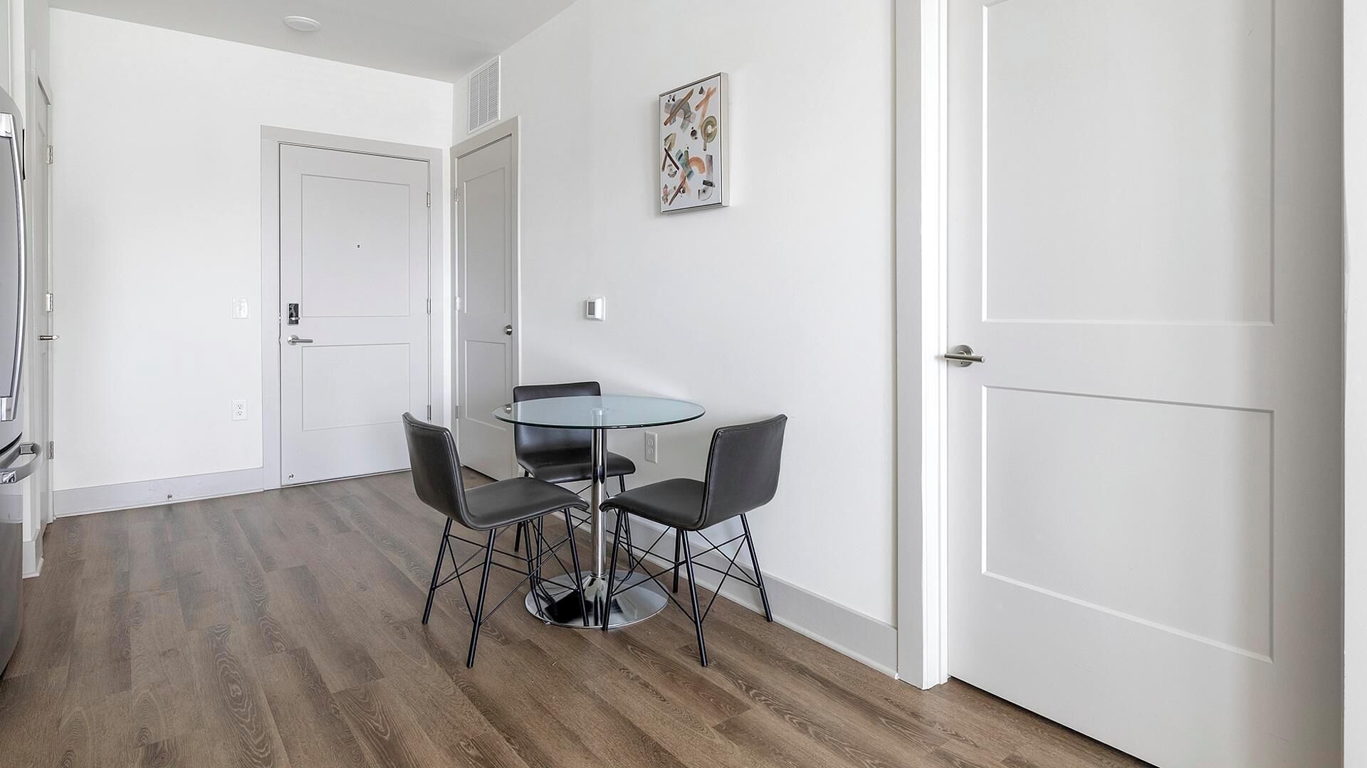 A modern kitchen with white cabinets, a stainless steel refrigerator, and a built-in oven.
