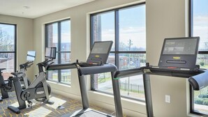 A gym with treadmills, stationary bikes, and a laptop on a desk.