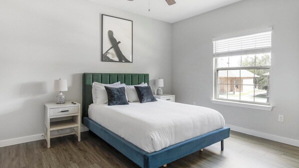 A bedroom with a bed, nightstands, a window, and a ceiling fan. - Landing | Stylish 1BD, Pool, Gym (Dallas)