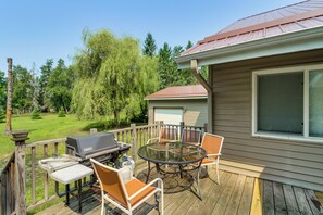 Eine Terrasse mit Grill, Stühlen und einem Tisch.
