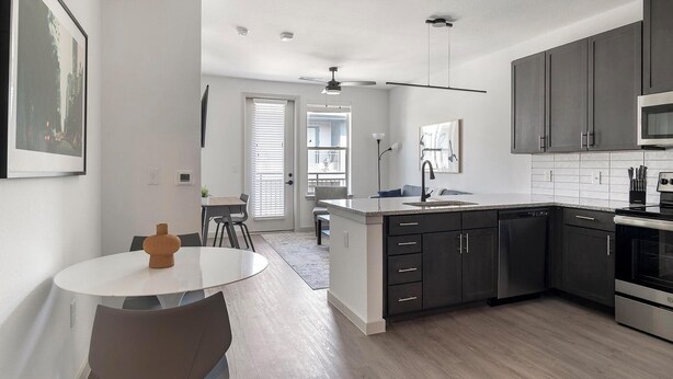 A modern kitchen with dark cabinets, a stainless steel oven, and a white countertop. - Landing | Amazing 1BD, Yoga Studio, Clubhouse (Dallas)