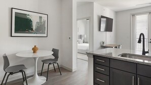 A modern kitchen with dark cabinets, a granite countertop, and a built-in sink. - Landing | Amazing 1BD, Yoga Studio, Clubhouse (Dallas)
