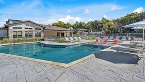 A swimming pool with lounge chairs and a covered area, surrounded by a stone deck and a building with a modern design. - Landing | Amazing 1BD, Yoga Studio, Clubhouse (Dallas)