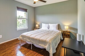 A bedroom with a bed, bedside tables, a nightstand, a window, and a ceiling fan. - Fish & Hike: Pet-Friendly Humble Home w/ Yard (Humble)