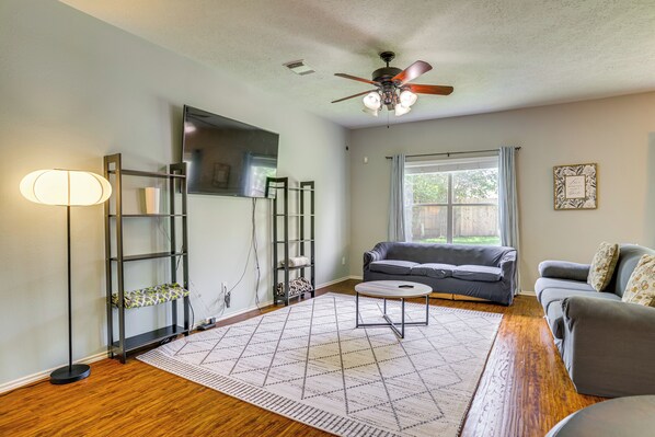 A living room with a ceiling fan, a sofa, a coffee table, and a floor lamp. - Fish & Hike: Pet-Friendly Humble Home w/ Yard (Humble)