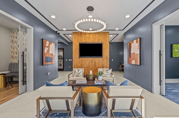 A modern living room with a large flat-screen TV, two sofas, a coffee table, and a wooden accent wall.