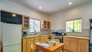 A kitchen with wooden cabinets, a dining table set for two, and a refrigerator. - Fish, Raft & Hike: Southwest OR Couple’s Retreat! (Trail)