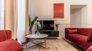 A modern living room with a red sofa, a marble coffee table, and a flat-screen TV.