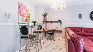 Ein modernes Wohnzimmer mit einem roten Ledersofa, einem Essbereich mit Metalleischen, einer Chandelier und einem Gemälde an der Wand.