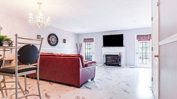 Ein geräumiges Wohnzimmer mit einem roten Sofa, einem Chandelier, einem Kamin und einem Fernseher.