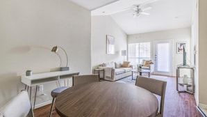 A modern living room with a dining table, sofa, and a ceiling fan.