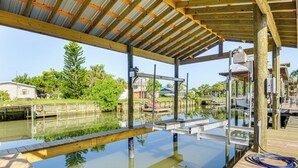 A covered dock area with a wooden deck, metal railing, and a clear view of the water and surrounding greenery. - Outdoor Oasis w/ Boat Slip & Spa in St Augustine! (St. Augustine)
