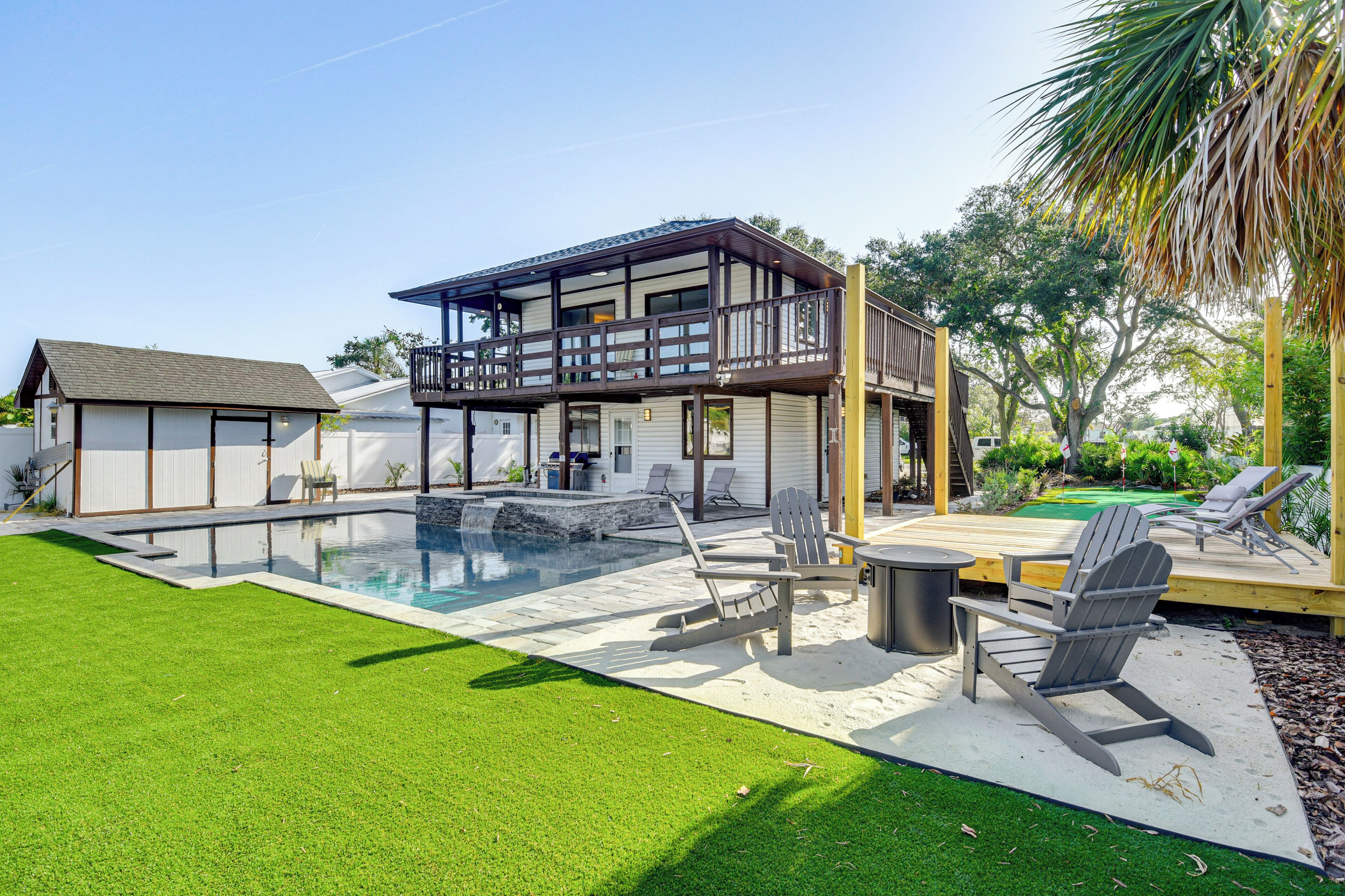 Ein modernes Haus mit einer großen Terrasse, einem Swimmingpool und Sitzgelegenheiten im Freien.