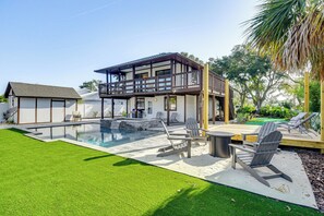 Et moderne hus med stor terrasse, swimmingpool og udendørs siddepladser.