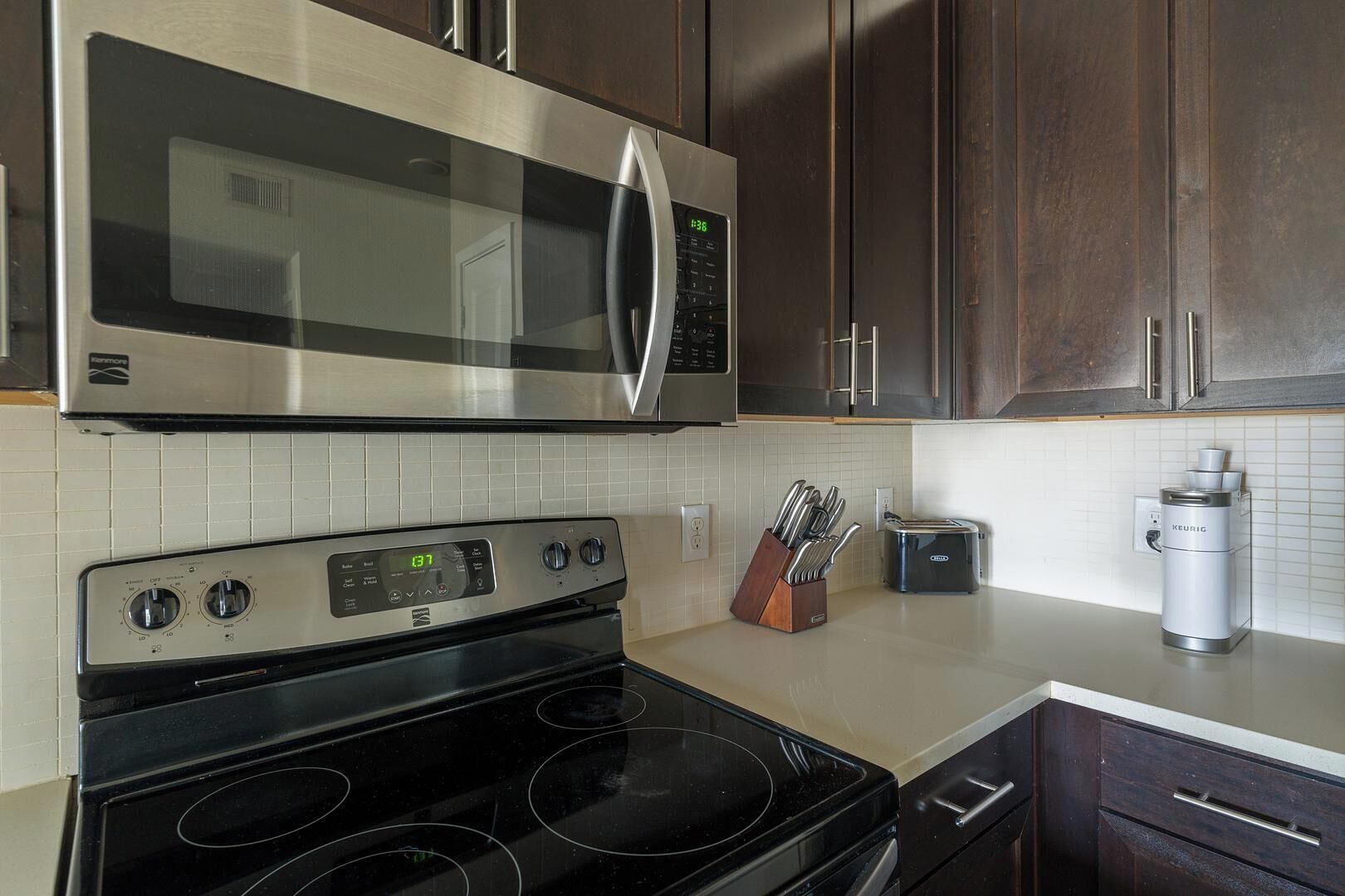 A kitchen with a stainless steel microwave, a built-in oven, a toaster, and a coffee maker.