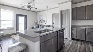 A modern kitchen with granite countertops, stainless steel appliances, and dark wood cabinets. - Landing | Stylish 1BD, Courtyard, Gym (Manor)