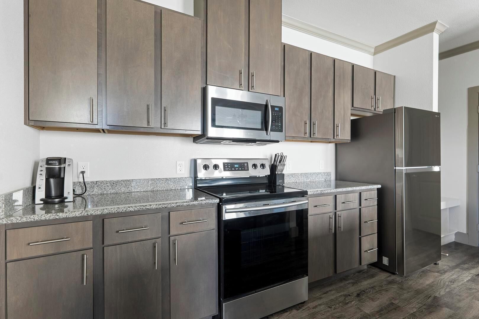 A modern kitchen with stainless steel appliances, wooden cabinets, and granite countertops.