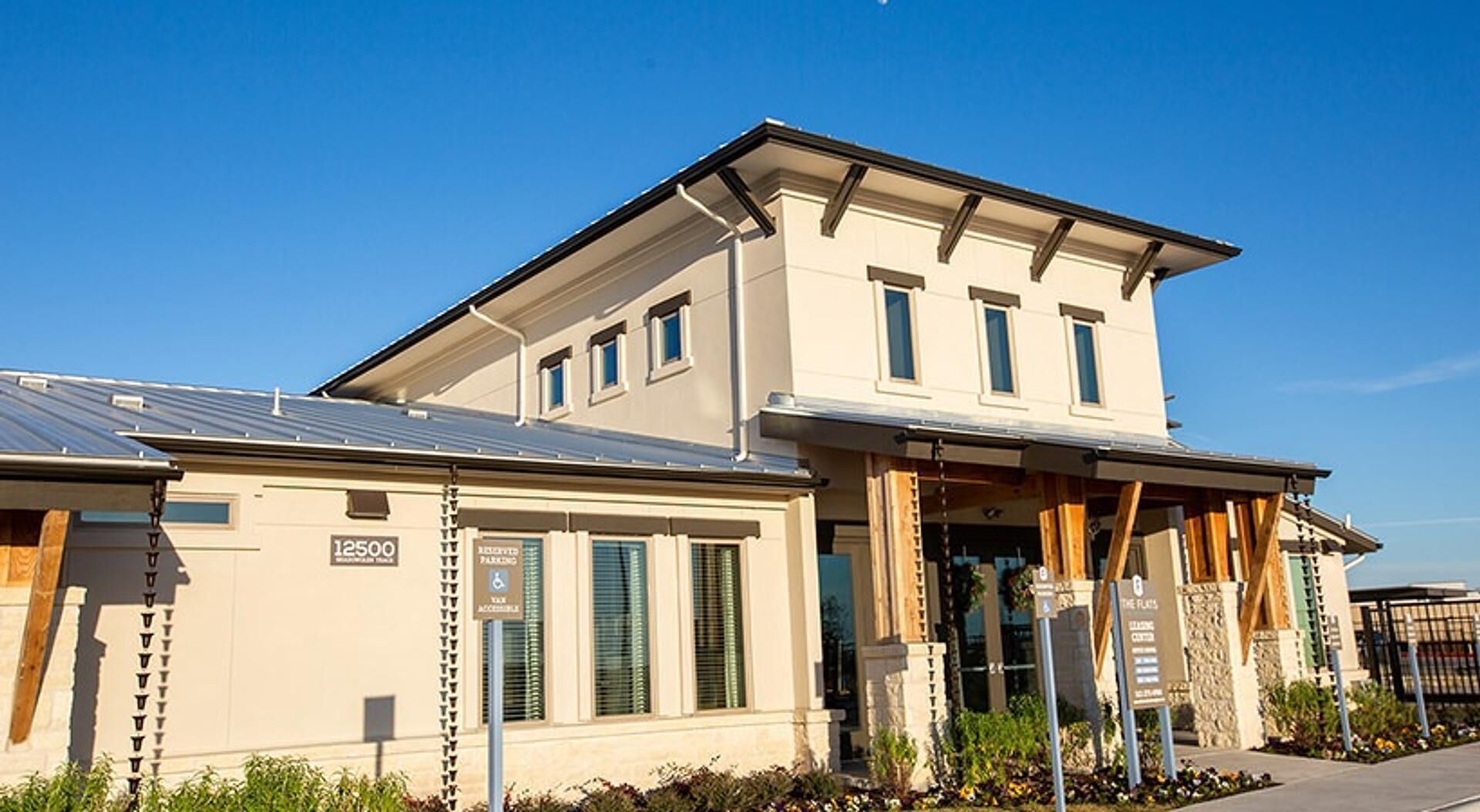 Een modern gebouw met twee verdiepingen, een plat dak, grote ramen en een overdekte entree.