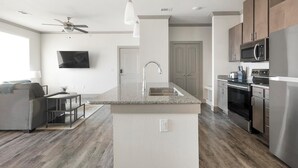A modern kitchen with a granite countertop, stainless steel appliances, and a built-in oven. - Landing | Spectacular 1BD, Courtyard, Gym (Manor)
