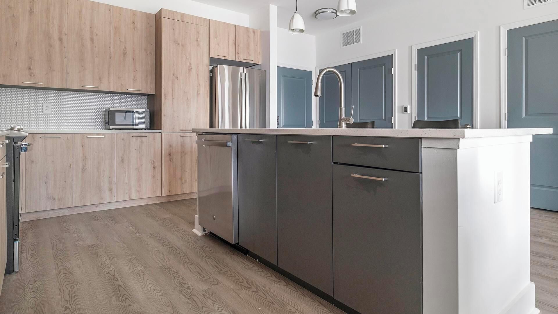 A modern kitchen with wooden cabinets, stainless steel appliances, and a white countertop.