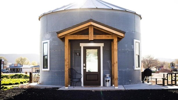 Un bâtiment cylindrique doté d’une porte d’entrée, d’un petit porche et d’un barbecue à l’extérieur.