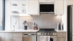 Une cuisine moderne avec des meubles blancs, une cuisinière en acier inoxydable, un four à micro-ondes et un lave-vaisselle.