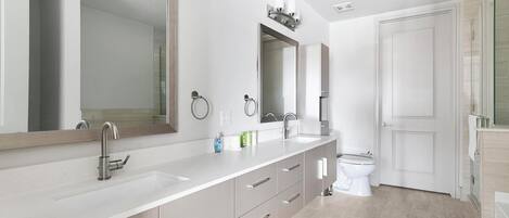 A modern bathroom with a large mirror, a sink, a toilet, and a shower area.