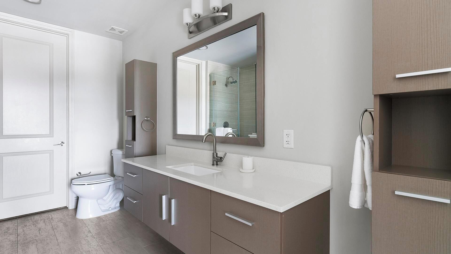 A modern bathroom with a white sink, a large mirror, and a toilet.