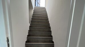 Eine Treppe mit Blick auf ein Gebäude durch eine offene Tür am oberen Ende.