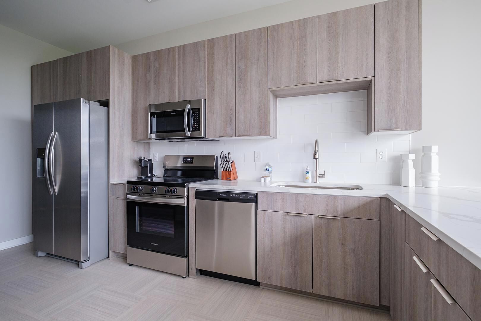 A modern kitchen with stainless steel appliances, a microwave, oven, and dishwasher, and light wood cabinetry.