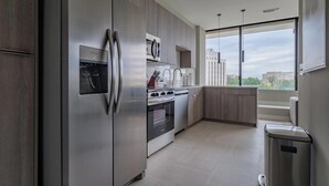 Cozinha moderna com eletrodomésticos de aço inoxidável, armários de madeira e uma janela ampla com vista para a cidade.