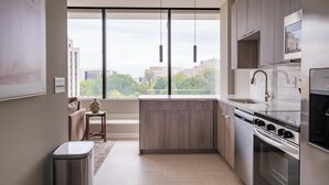 A modern kitchen with a large window, stainless steel appliances, and wooden cabinets. - Landing | Spectacular 1BD in Fountain Heights (Birmingham)