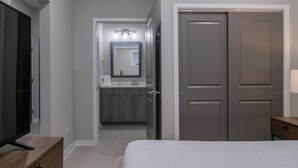 A bedroom with a bed, a TV on a wooden stand, a wardrobe, and a bathroom with a mirror and sink. - Landing | Spectacular 1BD in Fountain Heights (Birmingham)