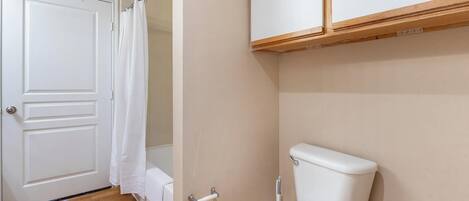 A bathroom with a white toilet, a shower curtain, and a door.