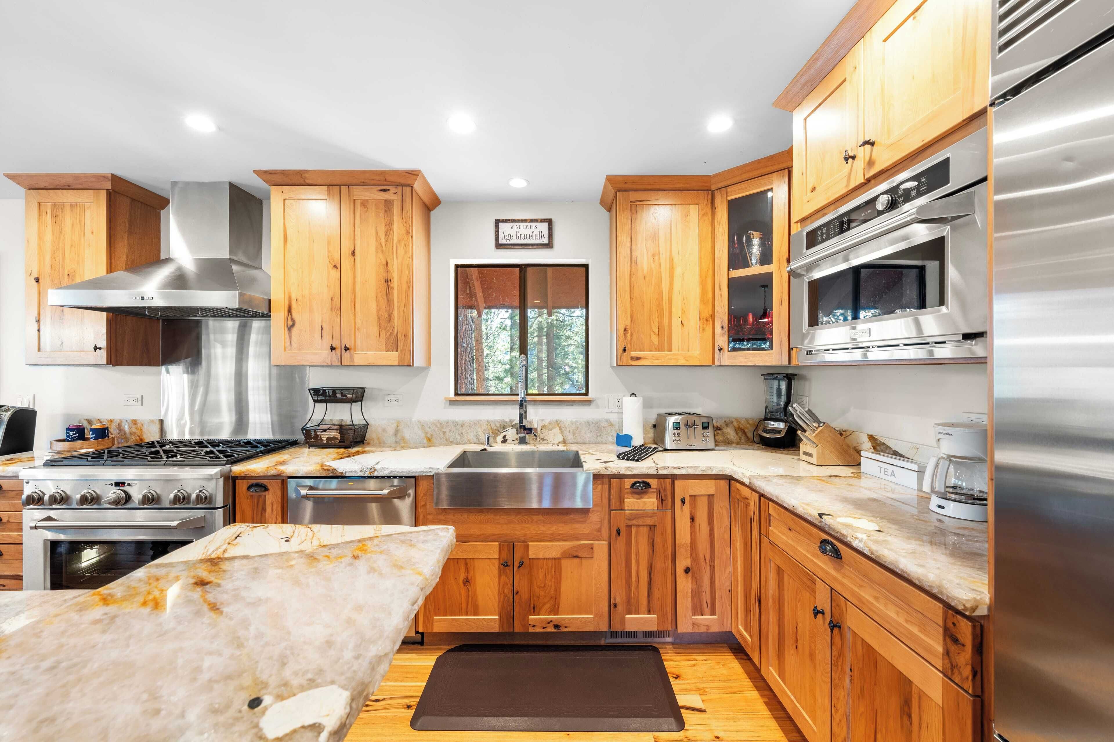 A modern kitchen with wooden cabinets, stainless steel appliances, and a large window.