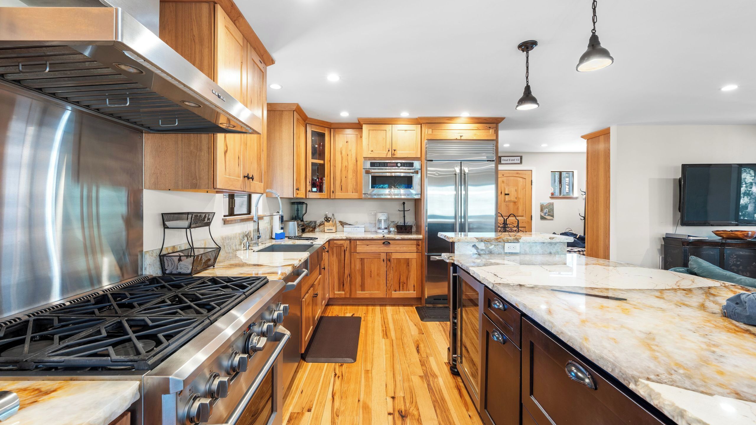 A modern kitchen with stainless steel appliances, wooden cabinets, and a marble countertop.