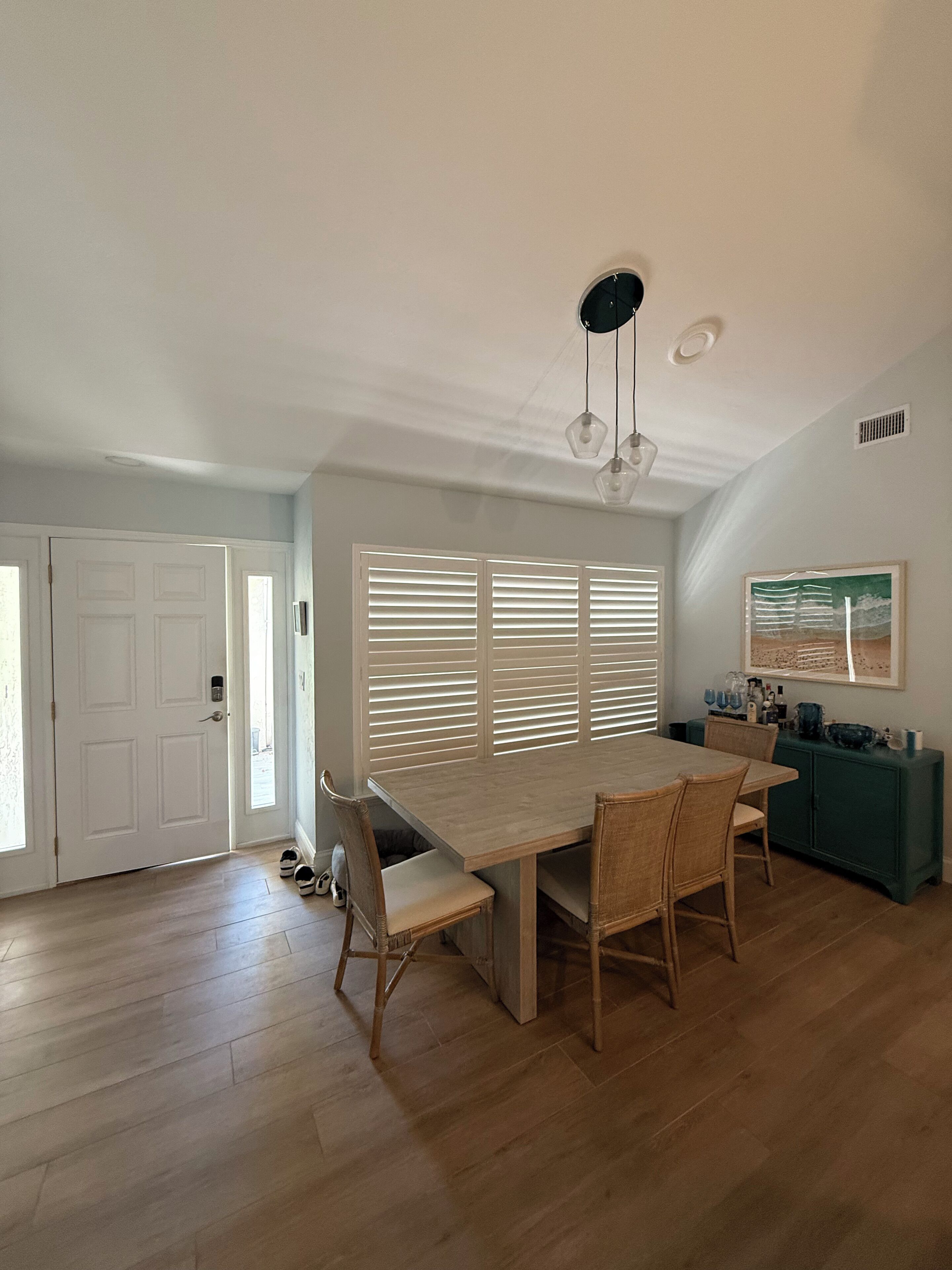 Un comedor amplio con una mesa y sillas de madera, un ventilador de techo y una ventana con persianas.