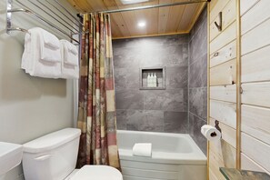 A bathroom with a toilet, bathtub, and shower curtain.