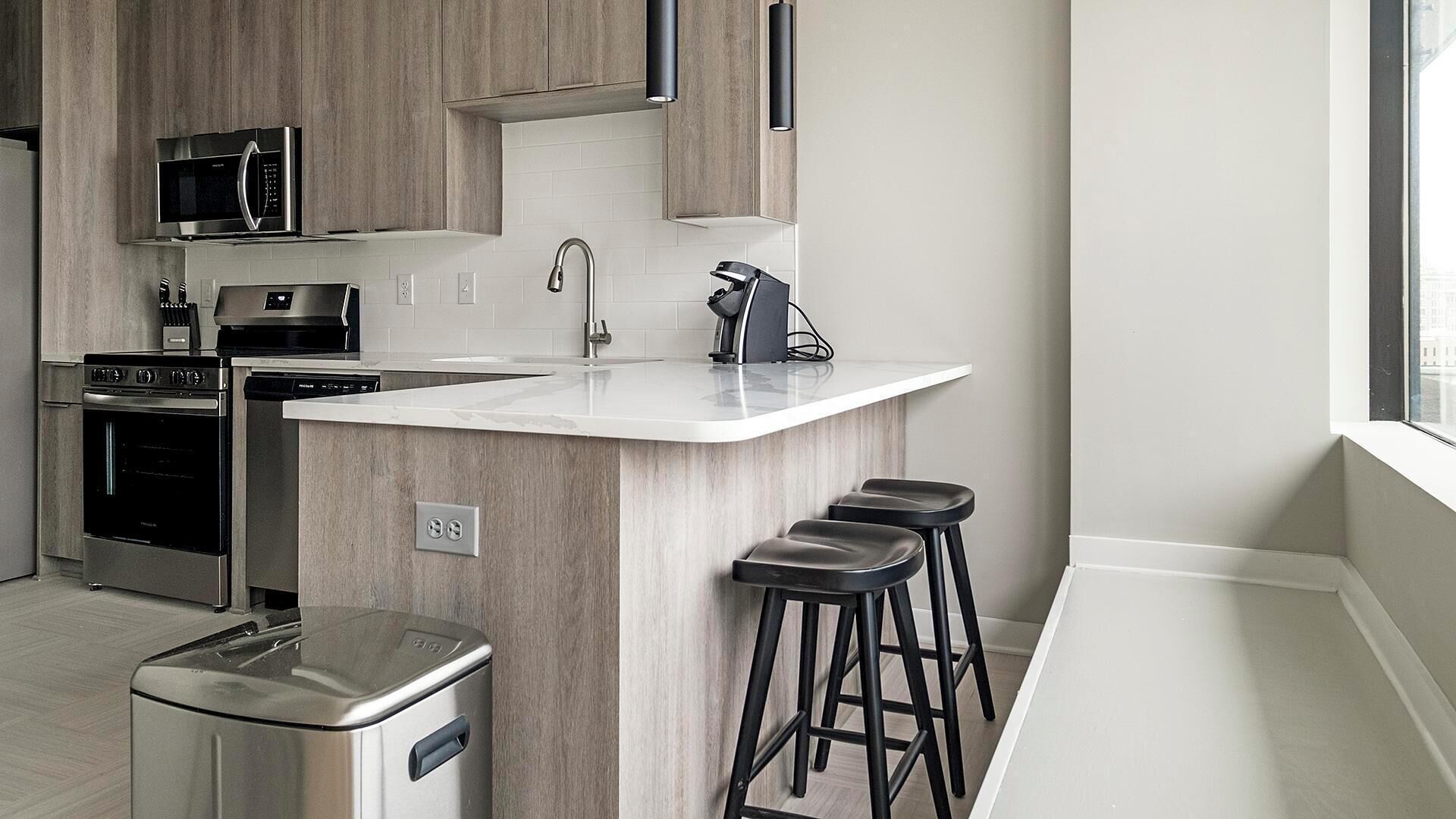 A modern kitchen with a central island, stainless steel appliances, and a window providing natural light.