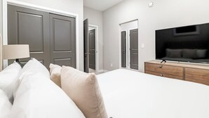 A hotel room with a bed, a TV, a dresser, and two doors. - Landing | Stylish 1BD in Fountain Heights (Birmingham)